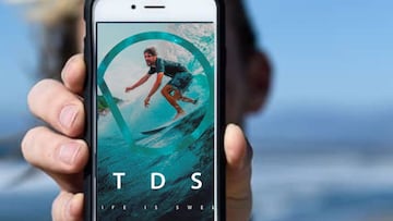 Un surfista muestra el tel&eacute;fono m&oacute;vil con la app de Todosurf, de previsi&oacute;n de oleaje. 