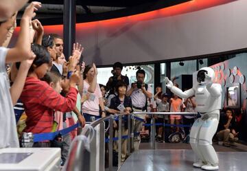 (FILES) This picture taken on July 3, 2013 shows Honda Motor's humanoid robot Asimo interacting with visitors at the National Museum of Emerging Science and Innovation in Tokyo on July 3, 2013.  Launched in 2000, the humanoid machine resembling a shrunken spaceman has become arguably Japan's most famous robot, wheeled out to impress visiting politicians over the years. / AFP PHOTO / YOSHIKAZU TSUNO