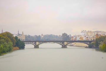 Imagen del río Guadalquivir con el puente de Triana, al fondo en el día que la llamada ‘lluvia de barro’, una combinación de una nube de polvo sahariano con una borrasca, que se ha producido esta mañana en la capital andaluza.