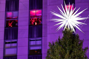 La gente mira por la ventana durante la 93.ª ceremonia anual de encendido del árbol de Navidad del Rockefeller Center.