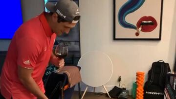 Jon Rahm emboca un putt mientras bebe una copa de vino.