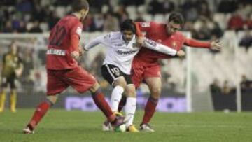 Banega, entre dos futbolistas de Osasuna.