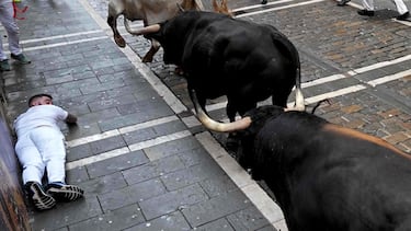Un participante cae junto a los toros durante el primer encierro de los Sanfermines en Pamplona.