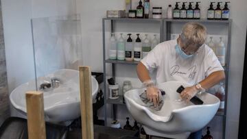 Madrid. 02/05/2020. Un empleado desinfecta con una disoluci&oacute;n de lej&iacute;a y agua la zona de corte, durante la visita a la peluquer&iacute;a Akaba Sal&oacute;n en Madrid, donde hoy han realizado las labores de limpieza y desinfecci&oacute;n y ha