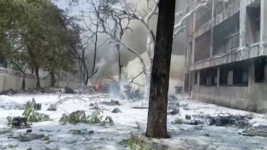 Humo se eleva cerca de un edificio dañado y árboles tras el accidente de un avión de Air India en Ahmedabad, India.