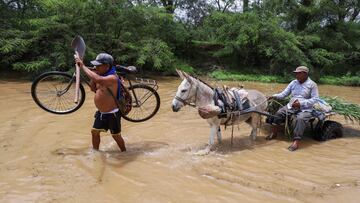 Residents cross through a stream flooded by the rains caused by the direct influence of Cyclone Yaku, in Piura, Peru, March 11, 2023. REUTERS/Sebastian Castaneda