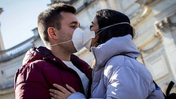 Imagen de una pareja bes&aacute;ndose con mascarilla.