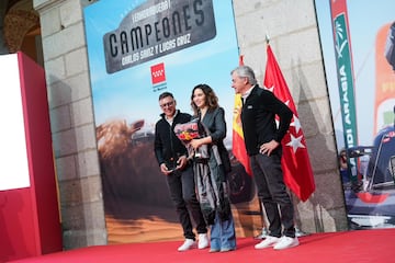Isabel Díaz Ayuso, presidenta de la Comunidad de Madrid, recibe un regalo de Carlos Sainz y Lucas Cruz en el homenaje por ganar el Rally Dakar 2024.
