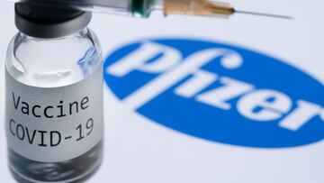 (FILES) In this file photo illustration taken on November 23, 2020, shows a syringe and a bottle reading &quot;Covid-19 Vaccine&quot; next to the Pfizer company logo. - The World Health Organization warned that vaccines were no magic bullet for the corona