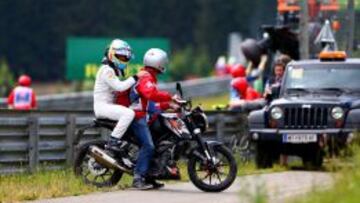 Fernando Alonso es llevado por un operario del circuito tras su accidente.