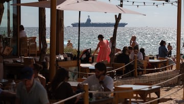 04 October 2025, Spain, Palma: People on the beach of Can Pere Antoni, while the US aircraft carrier "USS Gerald R. Ford" is anchored in the bay of Palma. The US Navy's largest and most modern warship arrived in Mallorca yesterday and is expected to stay until October 8. Photo: Clara Margais/dpa (Photo by Clara Margais/picture alliance via Getty Images)