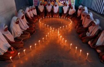 Las niñas de un colegio de Ahmedabad, India, forman un lazo de velas para conmemorar el día contra el Sida.