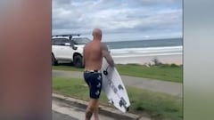 Surfista con tabla de surf viendo cómo roban un coche en la playa de Duranbah, Australia.