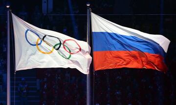 This file photo taken on February 7, 2014 in Sochi shows the Olympic and Russian flags being hoisted during the Opening Ceremony of the Sochi Winter Olympics