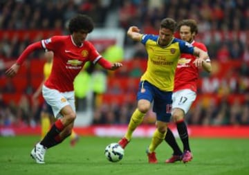 Olivier Giroud de Arsenal disputa la pelota con Marouane Fellaini y Daley Blind.