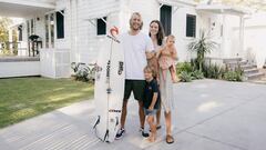 Owen Wright posa junto a su familia y una tabla de surf frente a una casa blanca en Australia que alquila por Airbnb. 