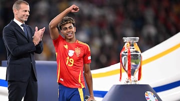 Spain's forward #19 Lamine Yamal reacts past Uefa president Aleksander Ceferin and next to the trophy after winning the UEFA Euro 2024 final football match between Spain and England at the Olympiastadion in Berlin on July 14, 2024. (Photo by Kirill KUDRYAVTSEV / AFP)