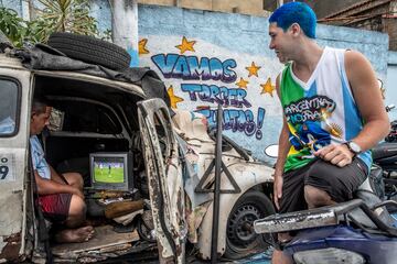 Unos aficionados ven el partido que enfrentó a Argentina con Polonia en un televisor dentro de un armazón de automóvil, en la comunidad de Dendê, en Río de Janeiro (Brasil). En la que está considerada la tercera favela más grande de Río, la mayoría de sus habitantes son fanáticos de la selección albiceleste.