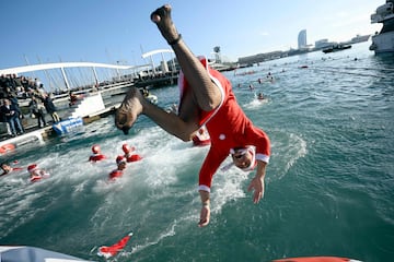 Un participante vestido de Santa Claus salta al agua de manera acrobática.