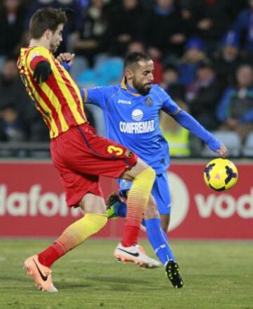 El defensa del Barcelona Gerard Piqué pelea un balón con el centrocampista del Getafe Diego Castro, en el partido de la decimoséptima jornada de la liga en Primera División que se disputa esta tarde en el Coliseo Alfonso Pérez.