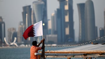 A boatman adjusts a Qatari national flag on his boat in Doha on November 7, 2022, ahead of the Qatar 2022 FIFA World Cup football tournament. (Photo by Kirill KUDRYAVTSEV / AFP)