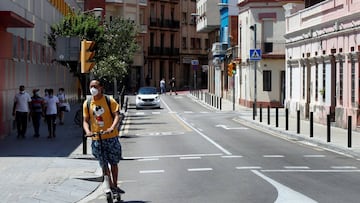 Imagen de un hombre que circula por la carretera con un patinete el&eacute;ctrico, y portando adem&aacute;s su mascarilla.