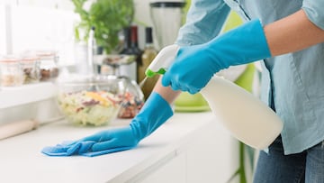 Woman cleaning and polishing the kitchen worktop with a spray detergent, housekeeping and hygiene concept