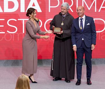 La presidenta de la Comunidad de Madrid, Isabel Díaz Ayuso (i), entrega una Encomienda a Benjamín Echeverría (c), padre superior de la Fraternidad de Jesús de Medinaceli, y a Miguel Ángel Izquierdo, vice hermano mayor de la Archicofradía, en representación de la Basílica de Nuestro Padre Jesús de Medinaceli en Madrid y la Archicofradía Primaria de la Real e Ilustre Esclavitud de Nuestro Padre Nazareno de Medinaceli.