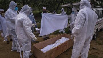 NEW DELHI, INDIA - JULY 17: Relatives cover the body the 35 years old Muslim man who died from the coronavirus disease (COVID-19), before burying it at the graveyard on July 17, 2020  in New Delhi, India. With the highest single-day surge of 34,956 cases,