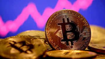 A representation of virtual currency Bitcoin is seen in front of a stock graph.