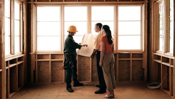 Husband and wife consulting with a architect inside a home under construction.
