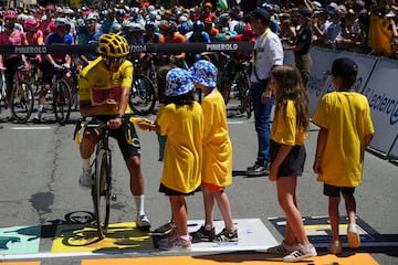 El ecuatoriano Richard Carapaz, vestido con el maillot amarillo de líder general, conversa con los aficionados al ciclismo mientras espera el inicio de la cuarta etapa del Tour de Francia en Pinerolo.