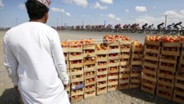 El pelotón rueda delante de un puesto de fruta.