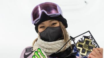 La snowboarder Chloe Kim, con mascarilla negra, máscara de nieve y la tabla de snowboard asomando por la parte izquierda, mostrando su medalla de oro en los X Games de Aspen (Colorado, Estados Unidos) 2021.