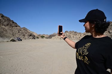 Una mujer usa su teléfono móvil para tomar una imagen del piloto belga Guillaume de Mevius y el copiloto francés Mathieu Baumel del X-Raid Team. 