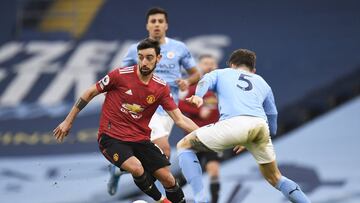 MANCHESTER, ENGLAND - MARCH 07: Bruno Fernandes of Manchester United runs with the ball whilst under pressure from John Stones of Manchester City during the Premier League match between Manchester City and Manchester United at Etihad Stadium on March 07, 