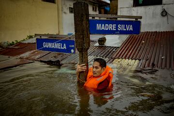 Un residente se agarra a un cartel en una calle inundada por el tifón Gaemi y las lluvias monzónicas el 24 de julio en la ciudad de Quezón, Metro Manila, Filipinas. Las lluvias monzónicas, intensificadas por el tifón Gaemi, provocaron inundaciones y deslizamientos de tierra en todo Filipinas, lo que provocó fallecidos y el desplazamiento de más de 600.000 personas. El tifón, que se ubicó al este de Taiwán con vientos de hasta 162 km/h, no tocó tierra en Filipinas, pero aumentó las lluvias monzónicas.