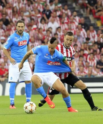 El defensa del Athletic Club Carlos Gurpegi (d) disputa el balón con el capitán eslovaco del Nápoles Marek Hamsik (c), durante el partido de vuelta de la fase previa de la Liga de Campeones que se disputa esta tarde en el estadio de San Mamés, en Bilbao. 