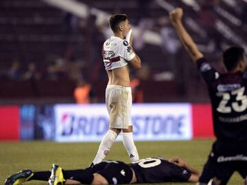 An Argentina's River Plate player reacts as Argentina's Lanus footballers celebrate after defeating River Plate by 4-2 and qualifying for the Copa Libertadores football final, at Lanus stadium in Lanus, Buenos Aires, Argentina, on October 31, 2017. / AFP PHOTO / JUAN MABROMATA