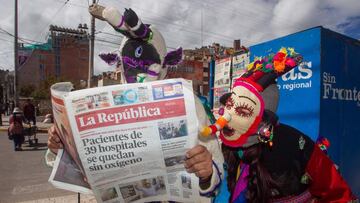 Two Kusillos, playful traditional Aymara harlequin-like characters from the Peruvian highlands, are seen reading a newspaper in Puno, Peru, on February 23, 2021. - Several people dressed like Kusillos walked in popular spots and markets in the highland city of Puno promoting social distancing and the mandatory use of face masks, as the city is currently on extreme alert in their fight against the spread of Covid-19. (Photo by Juan Carlos CISNEROS / AFP)