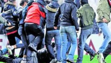 <b>PATEADO. </b>En la foto, varios hinchas que habían invadido el campo patean a otro aficionado sobre el césped.