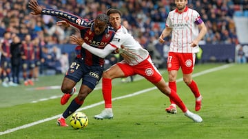 El defensa brasileño del Girona Vitor Reis (c) pelea un balón con el delantero camerunés del Levante Karl Etta Eyong.