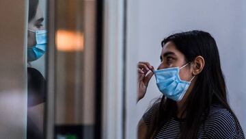 A woman wears a facemask as she talks to her friend at a shopping centre in Miami Beach, Florida on June 29, 2020. - The City of Miami issued an emergency order mandating facial coverings be worn in public at all times and until further notice. Officials will start issuing fines of up to $500 for not wearing a mask in public. (Photo by CHANDAN KHANNA / AFP)