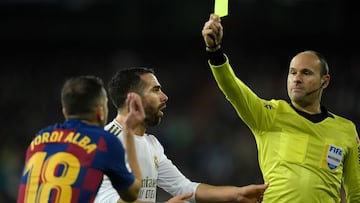 Spanish referee Mateu Lahoz hands a yellow card to Barcelona&#039;s Spanish defender Jordi Alba during the Spanish League football match between Real Madrid and Barcelona at the Santiago Bernabeu stadium in Madrid on March 1, 2020. (Photo by OSCAR DEL POZ