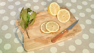 Lemons cut on a board, with a knife and laurel, natural appearance, on vintage tablecloth