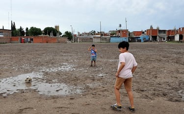 Dos niños juegan con un deteriorado balón en la vetusta y embarrada cancha del Club Atlético Estrella Roja, en Villa Fiorito, en la provincia de Buenos Aires. Esa misma cancha que años atrás tantas veces vio jugar, entre polvo y barro, a Diego Armando Maradona siendo apenas un niño, como los dos de la imagen.