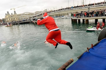 A participant in a Santa Claus suit jumps into the water during the 108th edition of the 'Copa Nadal' (Christmas Cup) swimming competition in Barcelona's Port Vell on December 25, 2017.  
The traditional 200-meter Christmas swimming race gathered more than 300 participants on Barcelona's old harbour.   / AFP PHOTO / Josep LAGO