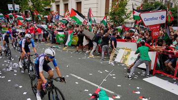 Riders of the Israel Premier Tech team compete as people holding Palestinian flags try to disrupt the eleventh stage of the Spanish Vuelta cycling race, from Bilbao to Bilbao, Spain, Wednesday, Aug. 3, 2025. (AP Photo/Miguel Oses)