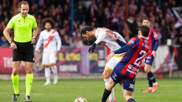 Sato trata de robar el balón a De Tomás.