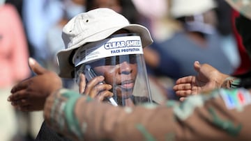 FILE PHOTO: A woman wears a protective face shield during food distribution, as South Africa starts to relax some aspects of a stringent nationwide coronavirus disease (COVID-19) lockdown, in Diepsloot near Johannesburg, South Africa, May 8, 2020. REUTERS